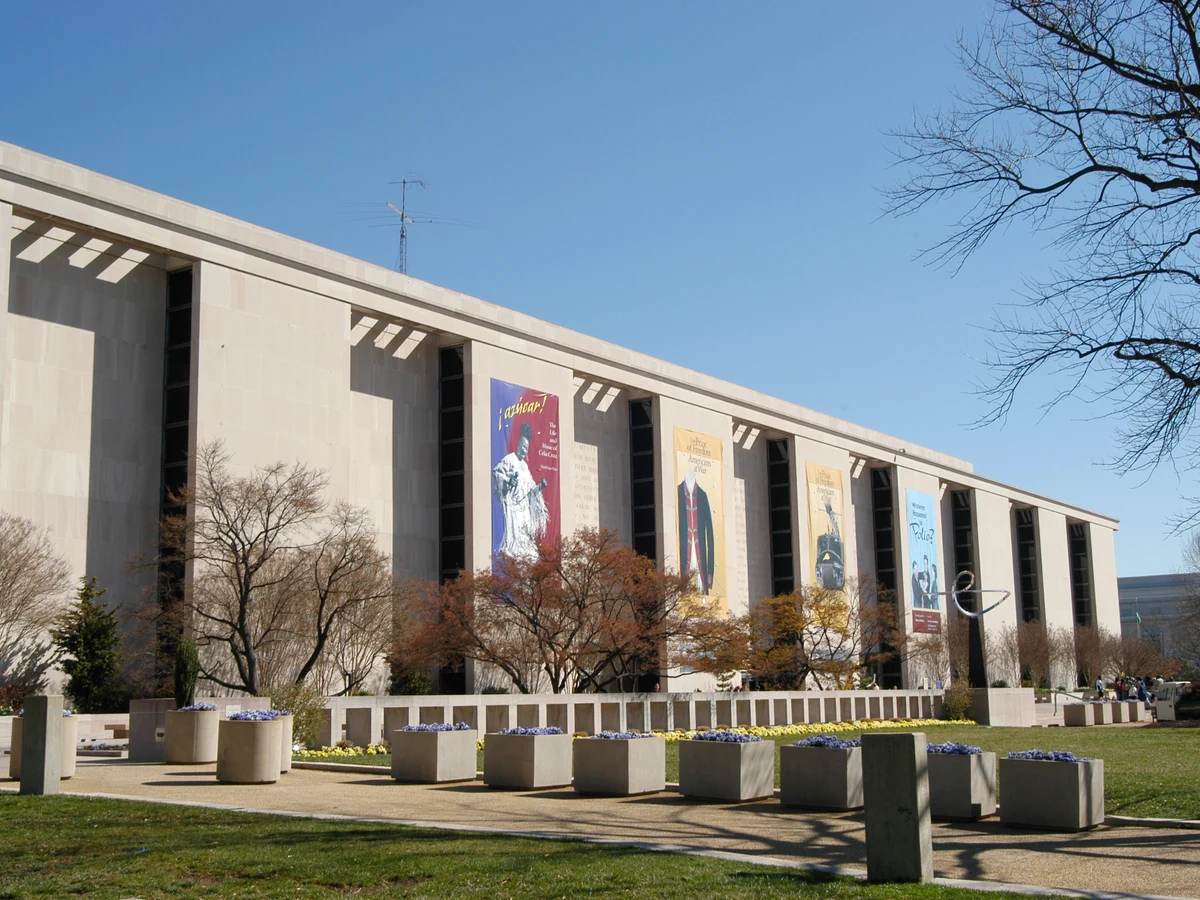 Exterior of the National Museum of American History, with banners, trees and plaza in front.