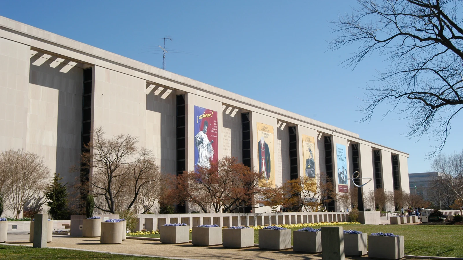 Exterior of the National Museum of American History, with banners, trees and plaza in front.