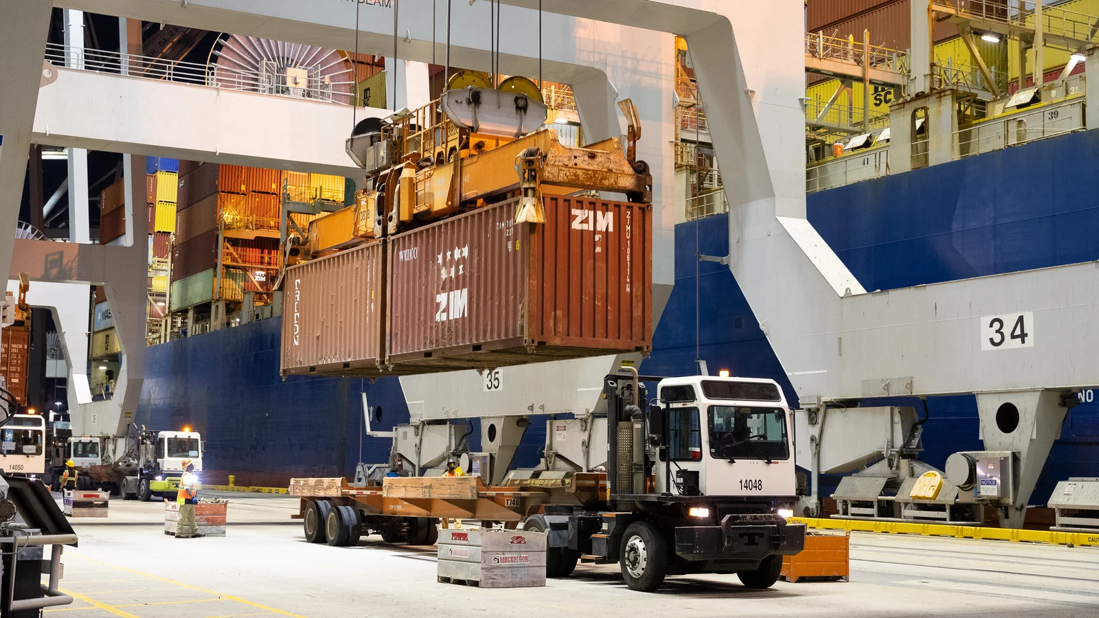 Container cranes lifting cargo from a ship at the Port of Savannah during evening light.
