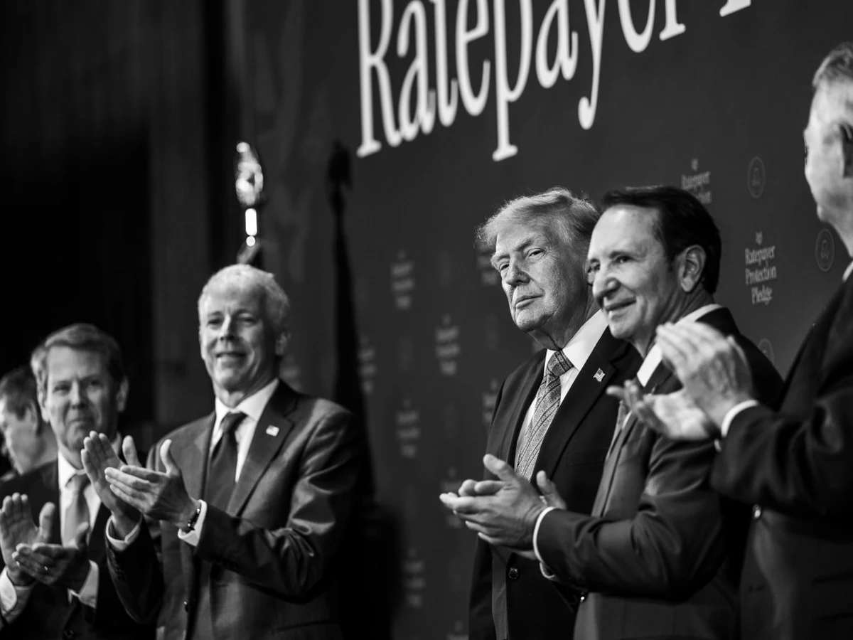 Black-and-white image of President Trump and other participants applauding at the pledge event.