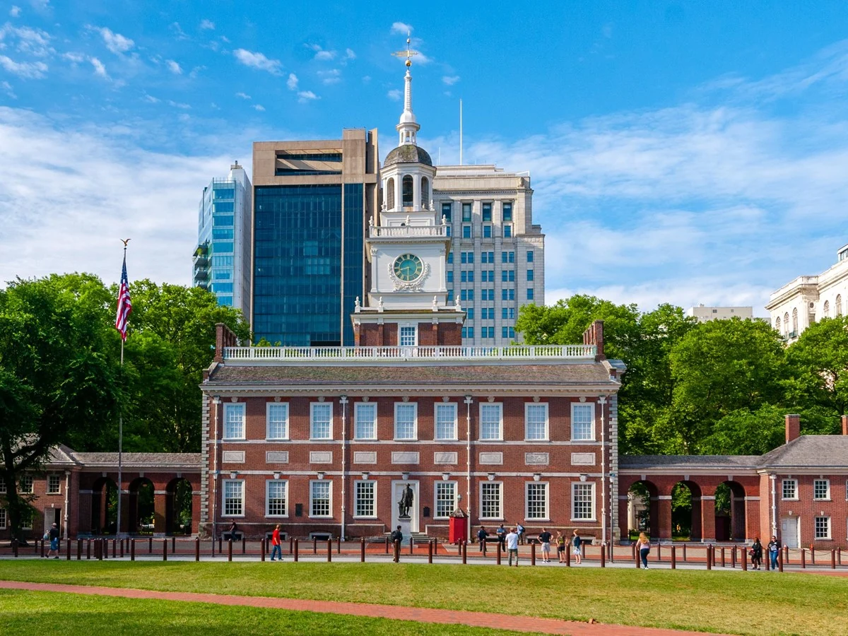 Independence Hall’s red-brick facade and white clock tower rise behind a lawn in Philadelphia.